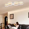 A woman is reading a book on a sofa in a living room, with a modern ceiling lamp overhead. Voir les images du produit
