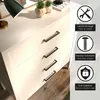 A close-up view of a white dresser with black handles, with marketing icons and text on the right side. Produktbild-Vorschau