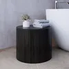 A dark wood cylindrical side table with a white vase and dried flowers, and a stack of folded towels on top, next to a white bathtub in a modern bathroom. Anteprima dell’immagine prodotto