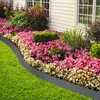 A garden bed with a variety of flowers and plants, bordered by a rattan-look edging and lawn. Produktbild-Vorschau