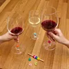 Three wine glasses with red and white wine are on a wooden table, with hands holding two of the glasses. Several colorful glass markers are scattered around a wooden stick with colorful rings. Podgląd zdjęcia produktu