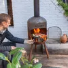 A man is grilling food on a BonFeu outdoor fireplace on a wooden deck. Anteprima dell’immagine prodotto