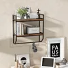 A wall-mounted shelf unit with books, a speaker, and decorative items, above a desk with a laptop and framed pictures. Produktbild-Vorschau