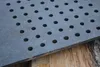 A close-up of a perforated cast iron grate resting on rough-hewn wood. Voir les images du produit