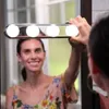 A woman is holding a makeup light bar in front of a mirror, reflecting her face. Produktbild-Vorschau