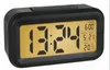 A black digital alarm clock with a yellow display showing the time, date, alarm setting, and temperature. Náhled obrázku produktu