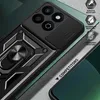 Close-up of a black phone case with a gold ring stand and camera slider, presented on a textured gray and green background. Produktbild-Vorschau