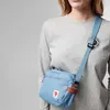 A person wearing a grey long-sleeved shirt and a blue crossbody bag. Anteprima dell’immagine prodotto