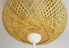 A close-up view of a woven bamboo lampshade with a white light fixture underneath. Produktbild-Vorschau