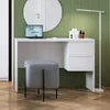 A modern white desk with a laptop, stool, and floor lamp against a green striped wall. Podgląd zdjęcia produktu