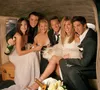 Six people are posing for a photo inside a vehicle, possibly a limousine, holding champagne bottles and glasses. Náhľad obrázku produktu