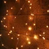 A close-up of a string of warm white micro LED lights with a silver wire, draped against a textured brown wall. Produktbild-Vorschau