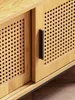 Close-up of a wooden cabinet with cane-woven sliding doors and a black handle. Produktbild-Vorschau