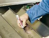 A person's hand is writing on a metal surface with a marker. Podgląd zdjęcia produktu