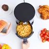 An overhead view of an air fryer with various foods around it, including a muffin, salmon, chicken, french fries, and tomatoes. Produktbild-Vorschau