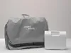 A gray bathing cushion in a storage bag and a white electronic device are placed on a light gray surface against a light gray background. Produktbild-Vorschau