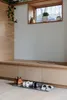 A shoe mat with shoes on it in front of a wooden cabinet and a window with plants. Náhled obrázku produktu
