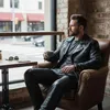 A man sitting in a chair at a cafe, drinking coffee and looking out the window. Produktbild-Vorschau