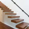 A modern interior staircase with floating wooden steps and a black metal handrail mounted on a white wall. Náhled obrázku produktu