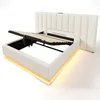A white upholstered bed frame with a slatted mattress base lifted to reveal storage space underneath. The bed has a padded headboard and LED lighting around the base. Produktbild-Vorschau