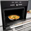 A casserole dish with melted cheese and a basil garnish is inside an open oven. Produktbild-Vorschau