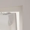 A close-up view of the top mechanism and cassette of a white roller blind, mounted in a window frame. Produktbild-Vorschau