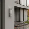 A modern gray outdoor wall light mounted on a gray textured wall next to a house with large windows. Podgląd zdjęcia produktu