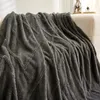 A dark gray plush blanket with a diamond pattern is draped over a sofa. Produktbild-Vorschau