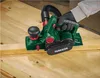 A person is using a green electric planer on a wooden surface. Produktbild-Vorschau