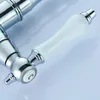 A close-up shot of a faucet handle with a white ceramic grip and chrome accents. Podgląd zdjęcia produktu