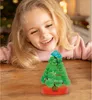 A young girl is looking at a small, crystal Christmas tree on a wooden table. Produktbild-Vorschau