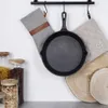 A cast iron skillet hangs on a rack with oven mitts and jars of food items in the background. Náhled obrázku produktu