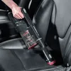 A hand holding a cordless vacuum cleaner to clean a car seat. Voir les images du produit