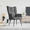 A dark gray velvet armchair is shown in a modern living room setting, with a floor lamp and a TV stand in the background. Voir les images du produit