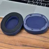 Two blue ear pads for headphones are placed on a wooden surface in front of a laptop. Podgląd zdjęcia produktu