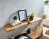 A wooden shelf with decorative items and books, placed above a desk. Náhled obrázku produktu