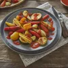 A close-up shot of a plate of roasted vegetables with a red sauce. Produktbild-Vorschau