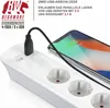 A white power strip with multiple outlets and two USB ports is shown, with a smartphone plugged into one of the USB ports and charging. Náhled obrázku produktu
