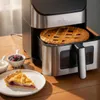 An air fryer with a pie inside, next to a slice of pie and bowls of toppings. Produktbild-Vorschau