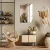A stylish living room corner with a rattan chair, a wooden cabinet, and decorative plants. Produktbild-Vorschau
