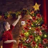 A young girl decorates a Christmas tree with ornaments. Produktbild-Vorschau