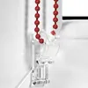 A close-up of a red beaded chain and a clear plastic bracket for a roller blind. Produktbild-Vorschau