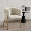 A fluffy white chair with gold legs is shown in a room with a small table and speaker.