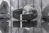 A close-up of a watch with a black leather strap, resting on a reflective surface with rocks in the background. Voir les images du produit