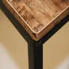 A close-up view of the corner of a desk with a wood-grain finish and black metal legs. Produktbild-Vorschau