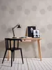 A desk with a chair, lamp, and artwork in a room with patterned wallpaper and wooden floor. Produktbild-Vorschau