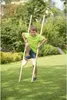 A young boy is using wooden stilts in a grassy yard. Anteprima dell’immagine prodotto