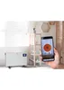 A person is holding a smartphone displaying a heating app next to a white electric heater in a room. Anteprima dell’immagine prodotto