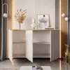 A white dresser with gold trim is shown with its doors open, revealing shelves. Decorative items like a bust, a painting, and dried flowers are on top of the dresser. Produktbild-Vorschau