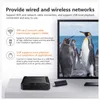 A black TV box and a USB drive are placed on a light gray surface in front of a large screen displaying penguins. Náhled obrázku produktu